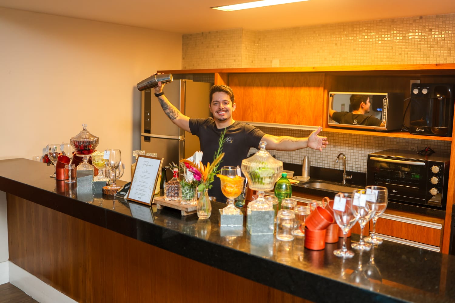 Bartender do Manhattan Bar sorrindo em bar de mármore com decoração floral